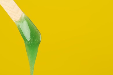 Wooden spatula with hot depilatory wax on yellow background. Space for text Photo of Wooden spatula with hot depilatory wax on yellow background. Space for text