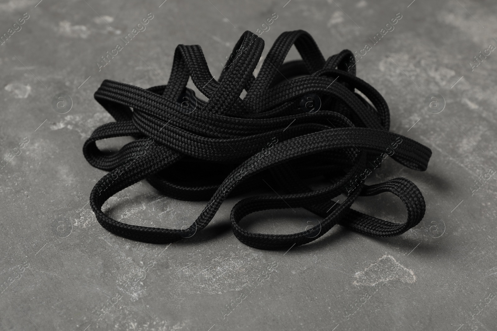 Black shoelace on grey stone background. Stylish accessory Photo of Black shoelace on grey stone background. Stylish accessory