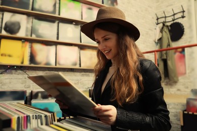 Young woman with vinyl record in store Image of Young woman with vinyl record in store