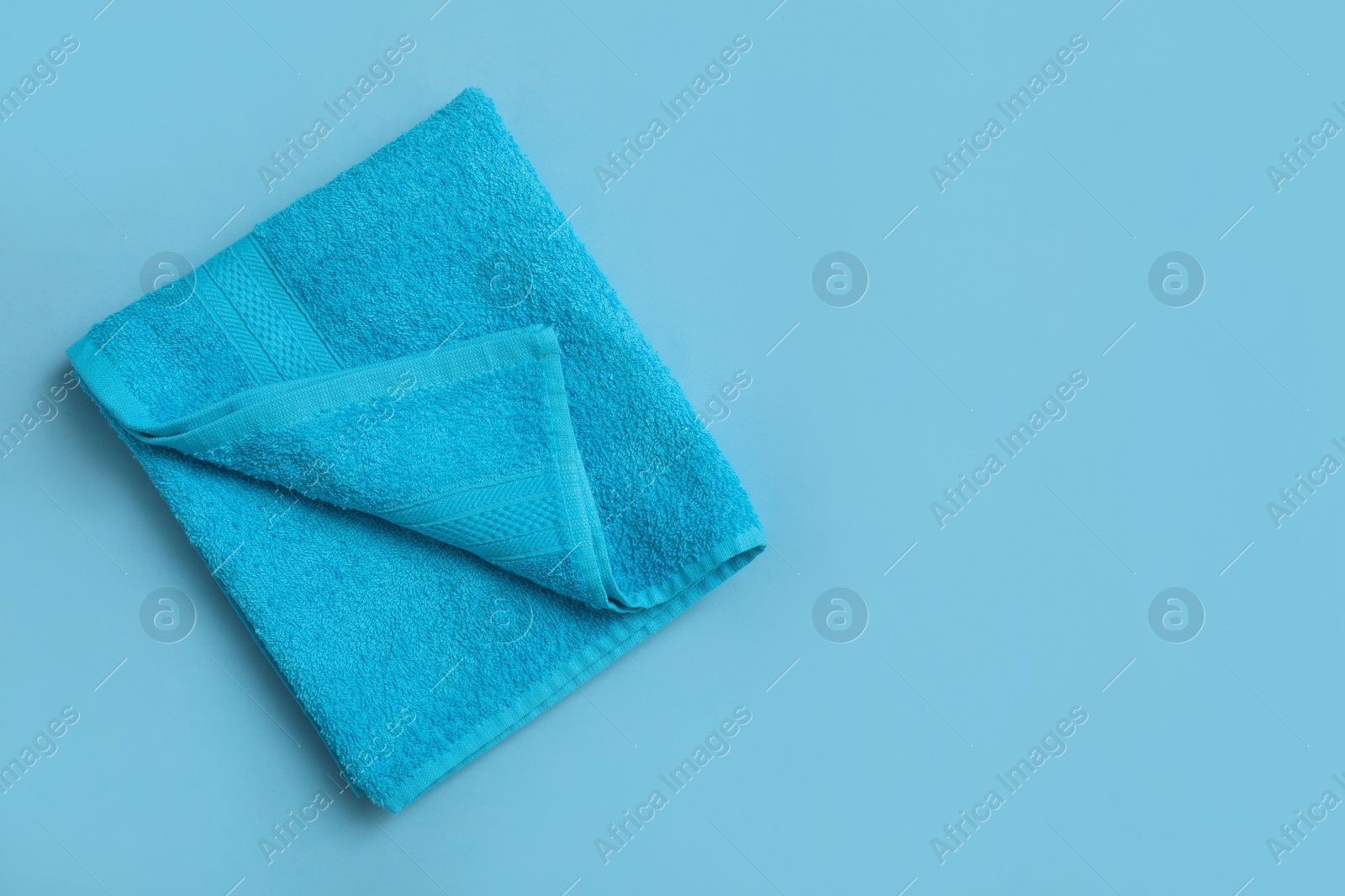 Folded soft beach towel on light blue background, top view. Space for text Photo of Folded soft beach towel on light blue background, top view. Space for text