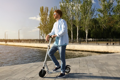 Man with modern kick scooter on waterfront Photo of Man with modern kick scooter on waterfront