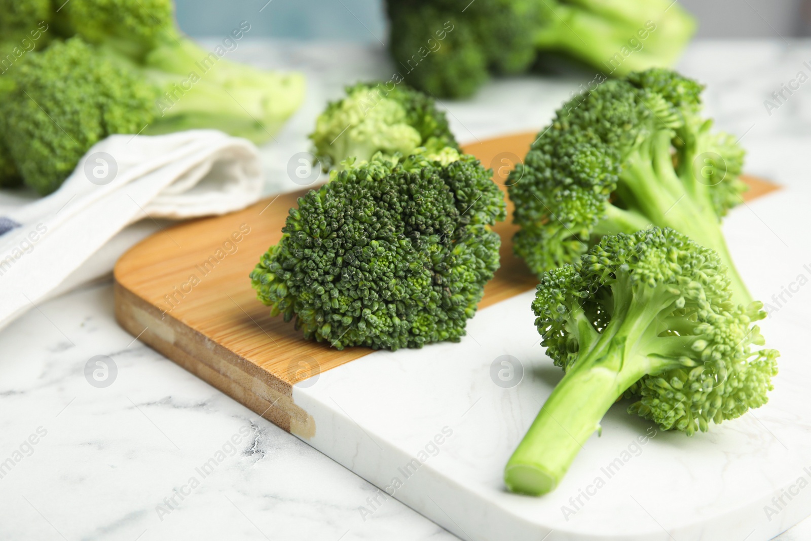 Photo of Fresh green broccoli on white marble table, closeup
