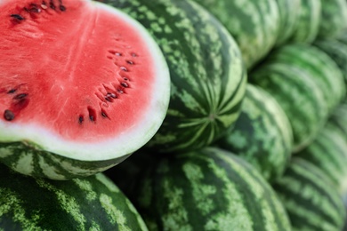 Delicious whole and cut watermelons as background, closeup Photo of Delicious whole and cut watermelons as background, closeup