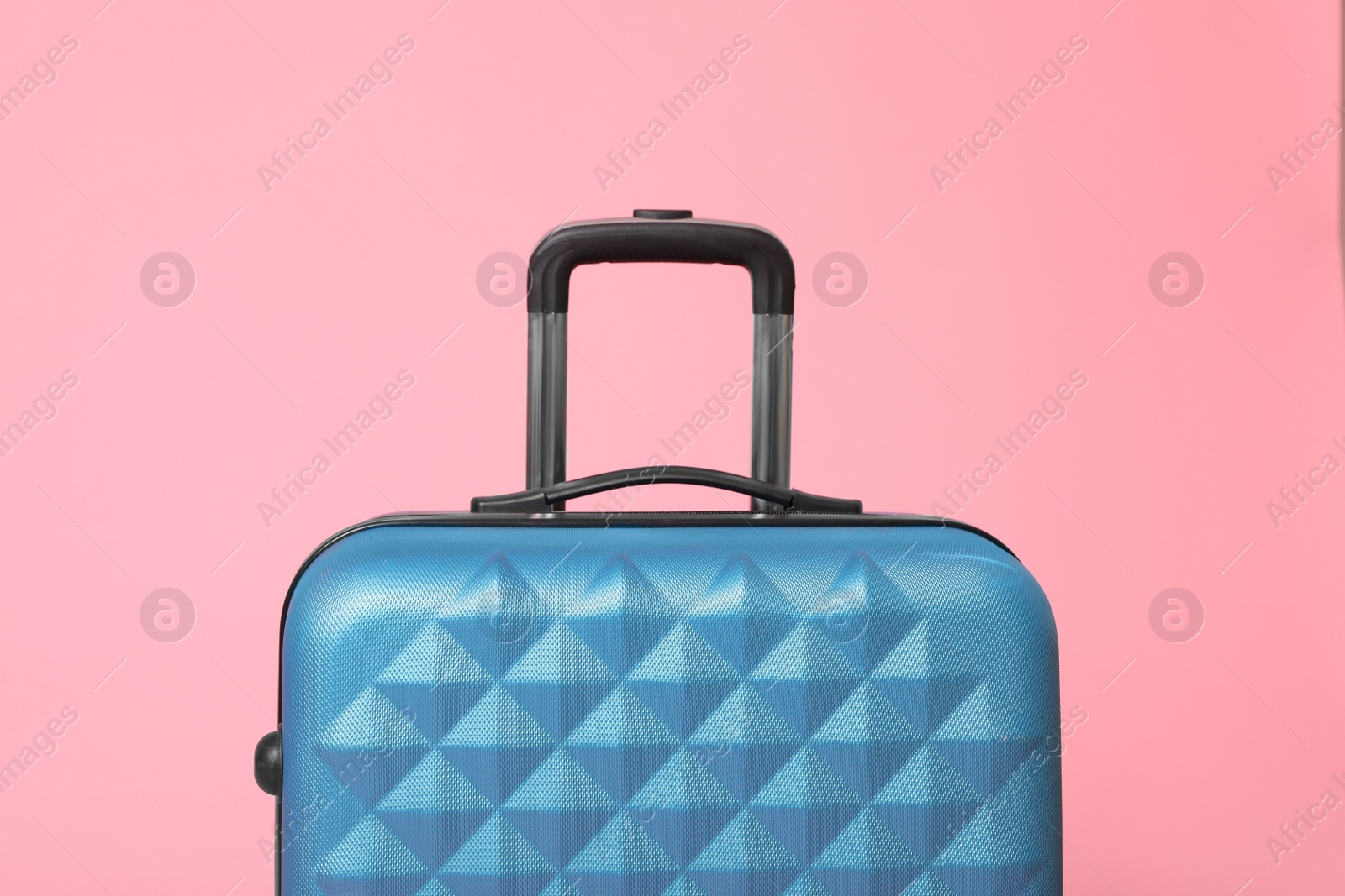 Photo of Stylish blue suitcase packed for travel on pink background