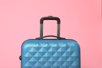 Photo of Stylish blue suitcase packed for travel on pink background