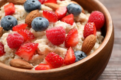 Tasty oatmeal porridge with berries and almond nuts in bowl, closeup Photo of Tasty oatmeal porridge with berries and almond nuts in bowl, closeup