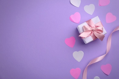 Gift box, ribbon and hearts on violet background, flat lay with space for text. Valentine's Day celebration Photo of Gift box, ribbon and hearts on violet background, flat lay with space for text. Valentine's Day celebration