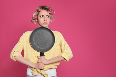 Young housewife with frying pan on pink background. Space for text Photo of Young housewife with frying pan on pink background. Space for text