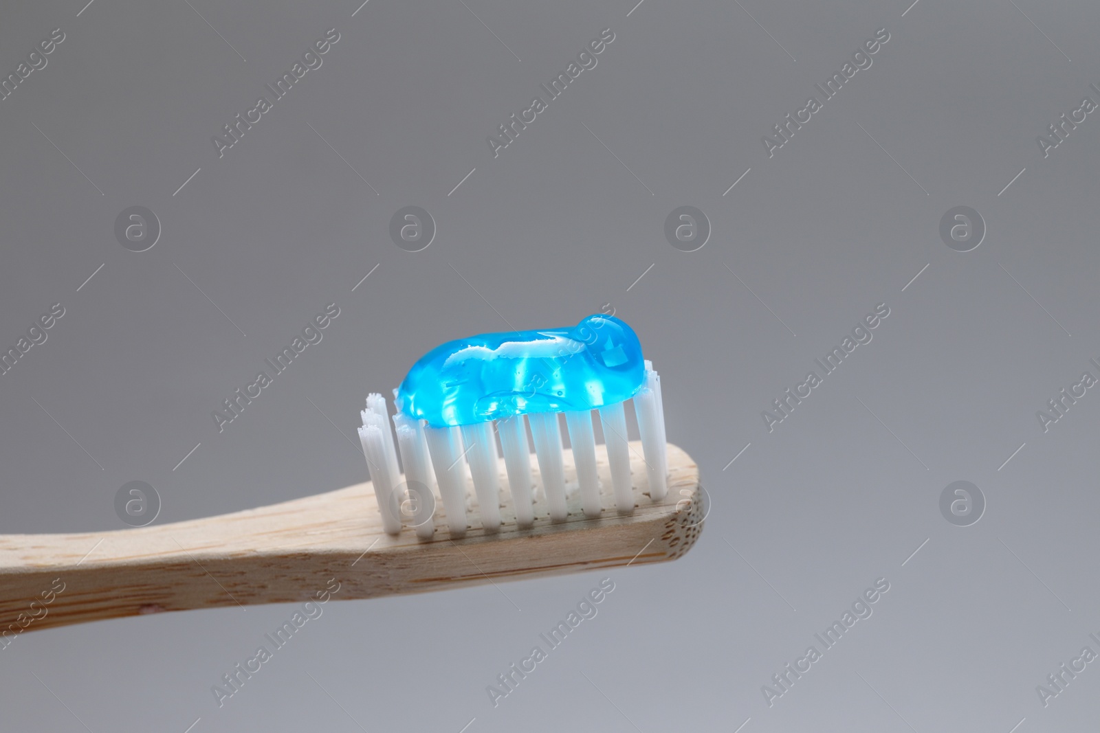 Wooden brush with toothpaste on grey background, closeup Photo of Wooden brush with toothpaste on grey background, closeup
