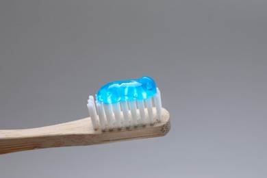 Wooden brush with toothpaste on grey background, closeup Photo of Wooden brush with toothpaste on grey background, closeup