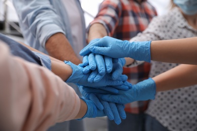 Group of people in blue medical gloves stacking hands indoors, closeup Photo of Group of people in blue medical gloves stacking hands indoors, closeup