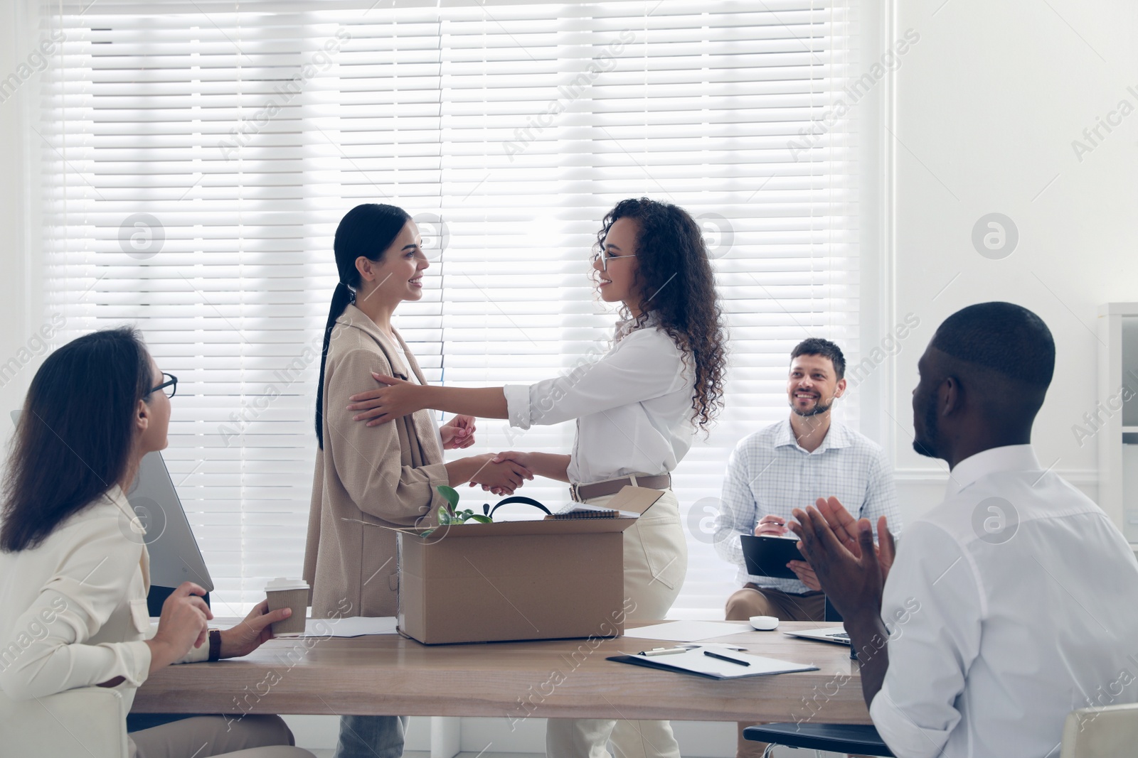 Boss shaking hand with new employee and coworkers applauding in office Photo of Boss shaking hand with new employee and coworkers applauding in office