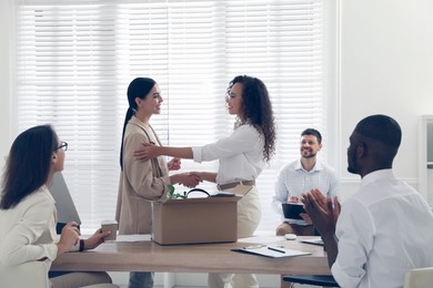 Boss shaking hand with new employee and coworkers applauding in office Photo of Boss shaking hand with new employee and coworkers applauding in office