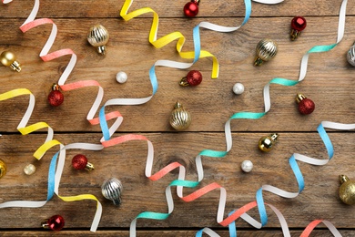 Colorful serpentine streamers and Christmas balls on wooden background, flat lay Photo of Colorful serpentine streamers and Christmas balls on wooden background, flat lay