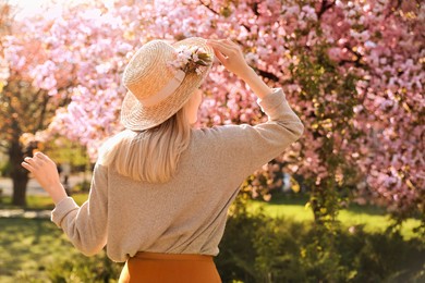 Young woman wearing stylish outfit in park on spring day, back view. Fashionable look Photo of Young woman wearing stylish outfit in park on spring day, back view. Fashionable look