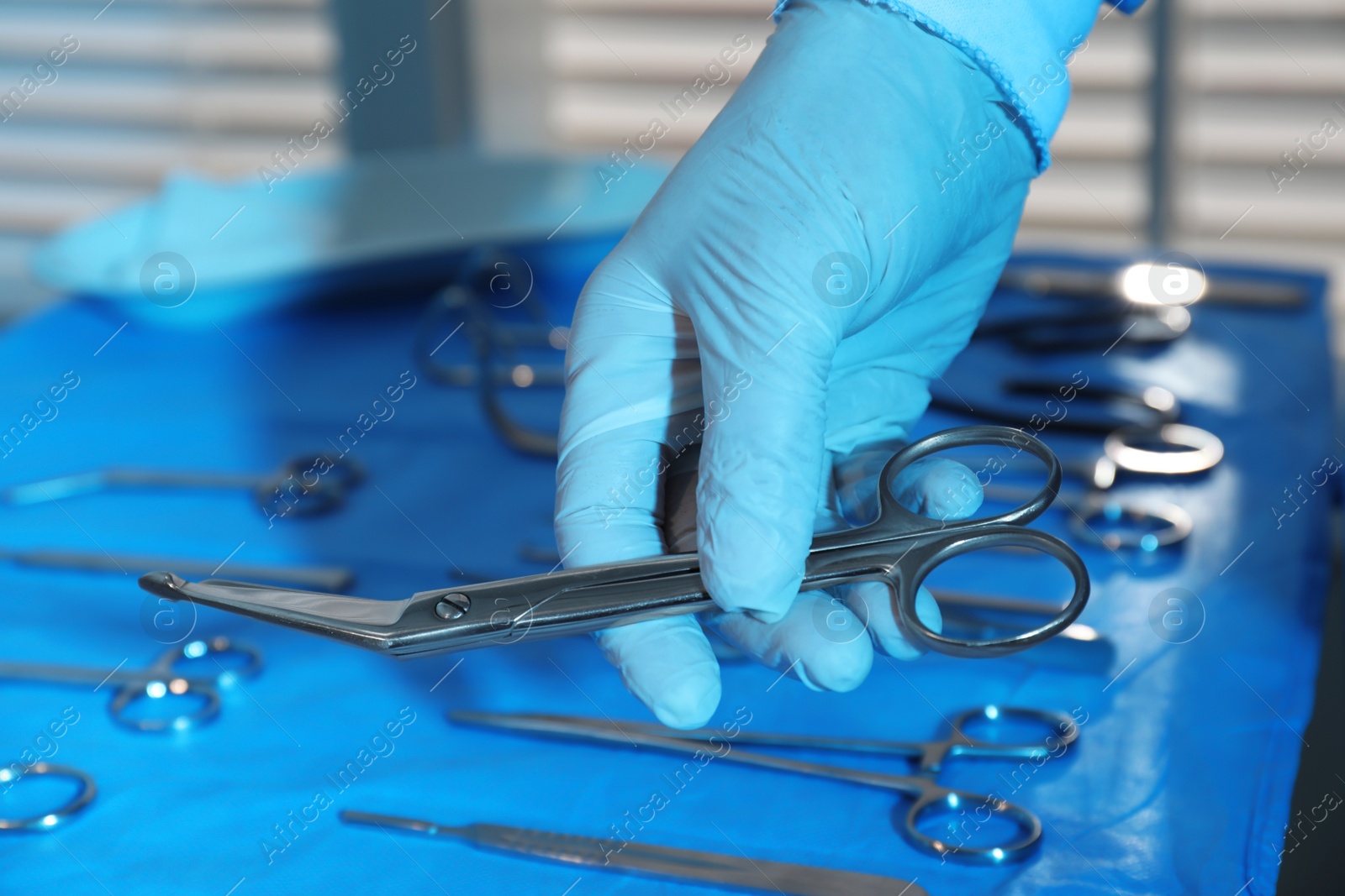 Doctor taking Pott's scissors from table with different surgical instruments indoors, closeup Photo of Doctor taking Pott's scissors from table with different surgical instruments indoors, closeup