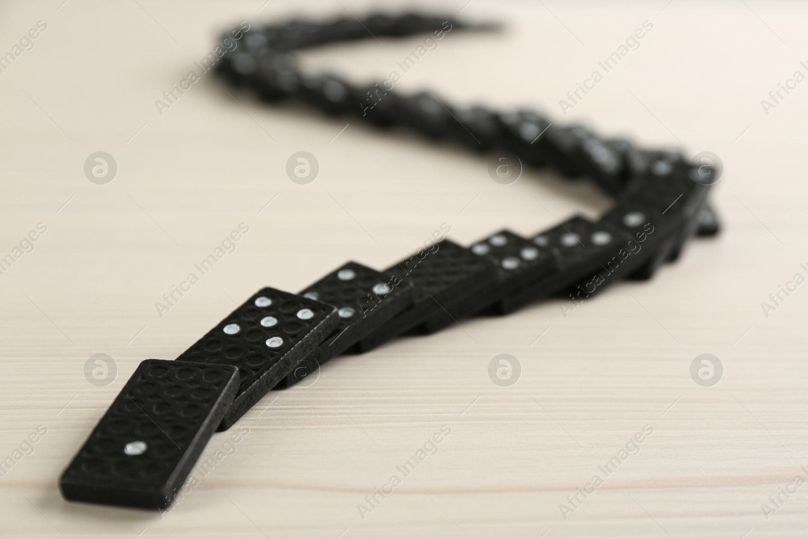 Photo of Fallen black domino tiles on white table