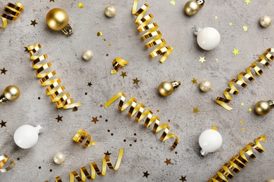 Shiny serpentine streamers and Christmas balls on grey background, flat lay Photo of Shiny serpentine streamers and Christmas balls on grey background, flat lay