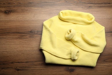 Yellow warm sweater on wooden table, top view. Space for text Photo of Yellow warm sweater on wooden table, top view. Space for text