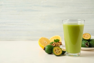 Fresh feijoa smoothie in glass on white table, space for text Photo of Fresh feijoa smoothie in glass on white table, space for text