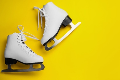 Pair of figure ice skates on yellow background, flat lay. Space for text Photo of Pair of figure ice skates on yellow background, flat lay. Space for text