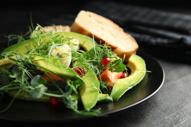 Salad with fresh organic microgreen in plate on black table, closeup Photo of Salad with fresh organic microgreen in plate on black table, closeup