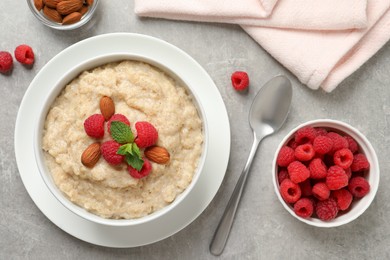 Tasty oatmeal porridge with raspberries and almond nuts served on light grey table, flat lay Photo of Tasty oatmeal porridge with raspberries and almond nuts served on light grey table, flat lay