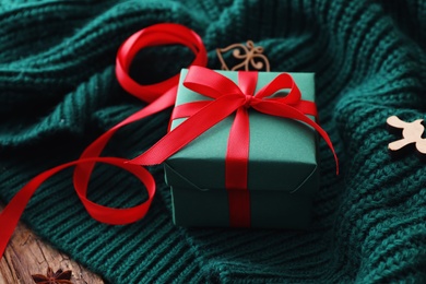 Christmas gift box on green knitted cloth, closeup Photo of Christmas gift box on green knitted cloth, closeup