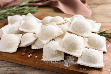 Uncooked ravioli and rosemary on wooden table, closeup Photo of Uncooked ravioli and rosemary on wooden table, closeup