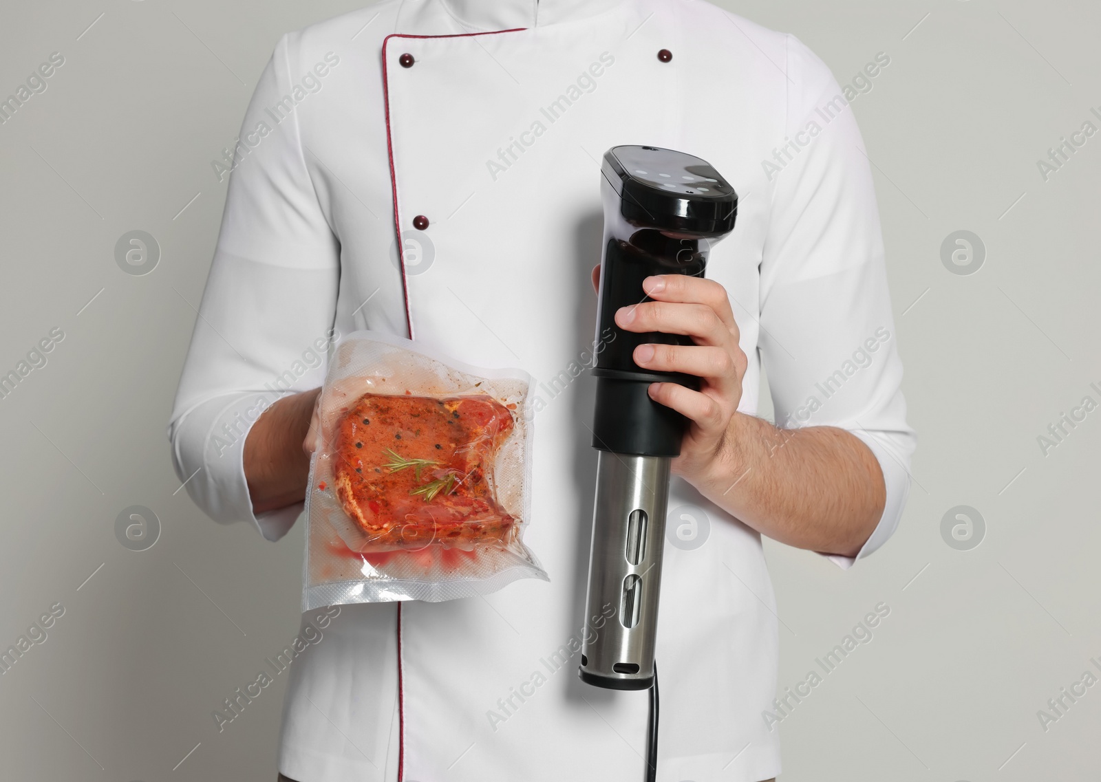 Chef holding sous vide cooker and meat in vacuum pack on beige background, closeup Photo of Chef holding sous vide cooker and meat in vacuum pack on beige background, closeup
