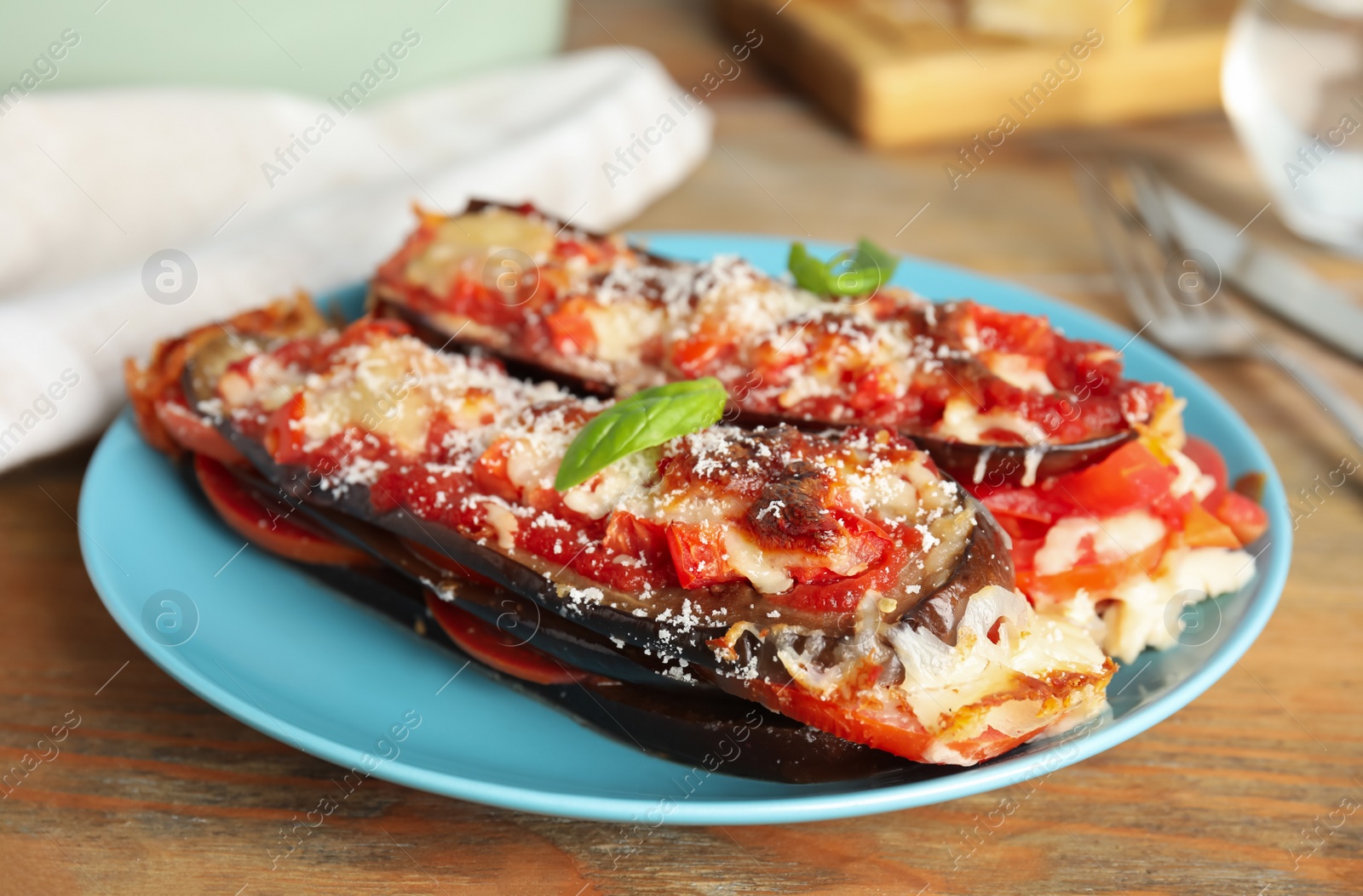 Baked eggplant with tomatoes, cheese and basil on wooden table, closeup Photo of Baked eggplant with tomatoes, cheese and basil on wooden table, closeup