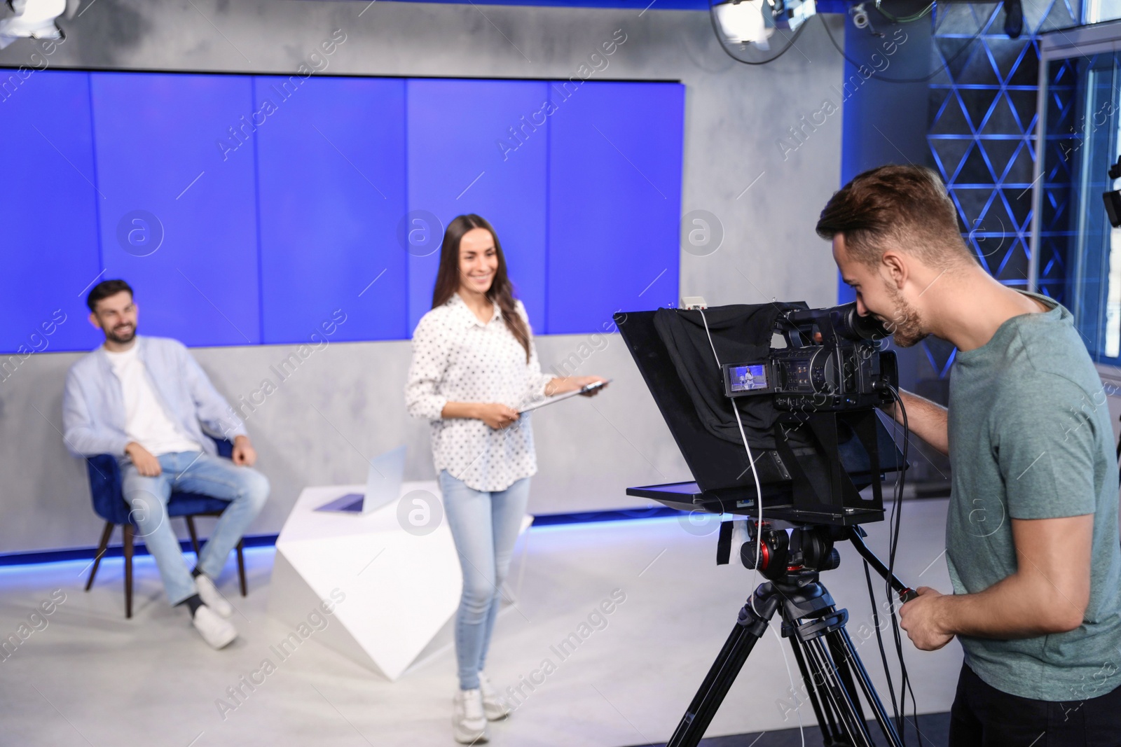 Presenters and video camera operator working in studio. News broadcasting Photo of Presenters and video camera operator working in studio. News broadcasting