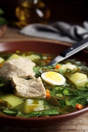 Delicious sorrel soup with meat and egg in brown bowl, closeup Photo of Delicious sorrel soup with meat and egg in brown bowl, closeup