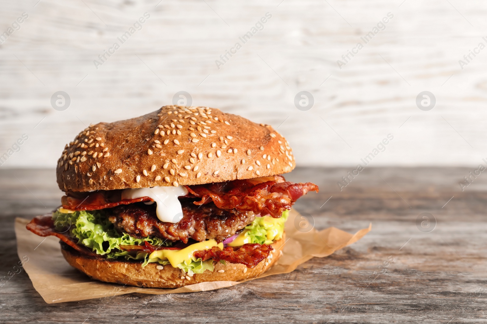 Tasty burger with bacon on wooden table Photo of Tasty burger with bacon on wooden table