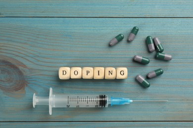 Cubes with word Doping and drugs on light blue wooden background, flat lay Photo of Cubes with word Doping and drugs on light blue wooden background, flat lay