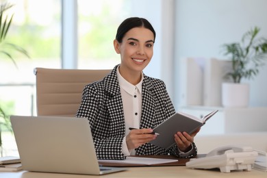 Secretary working at wooden table in office Photo of Secretary working at wooden table in office