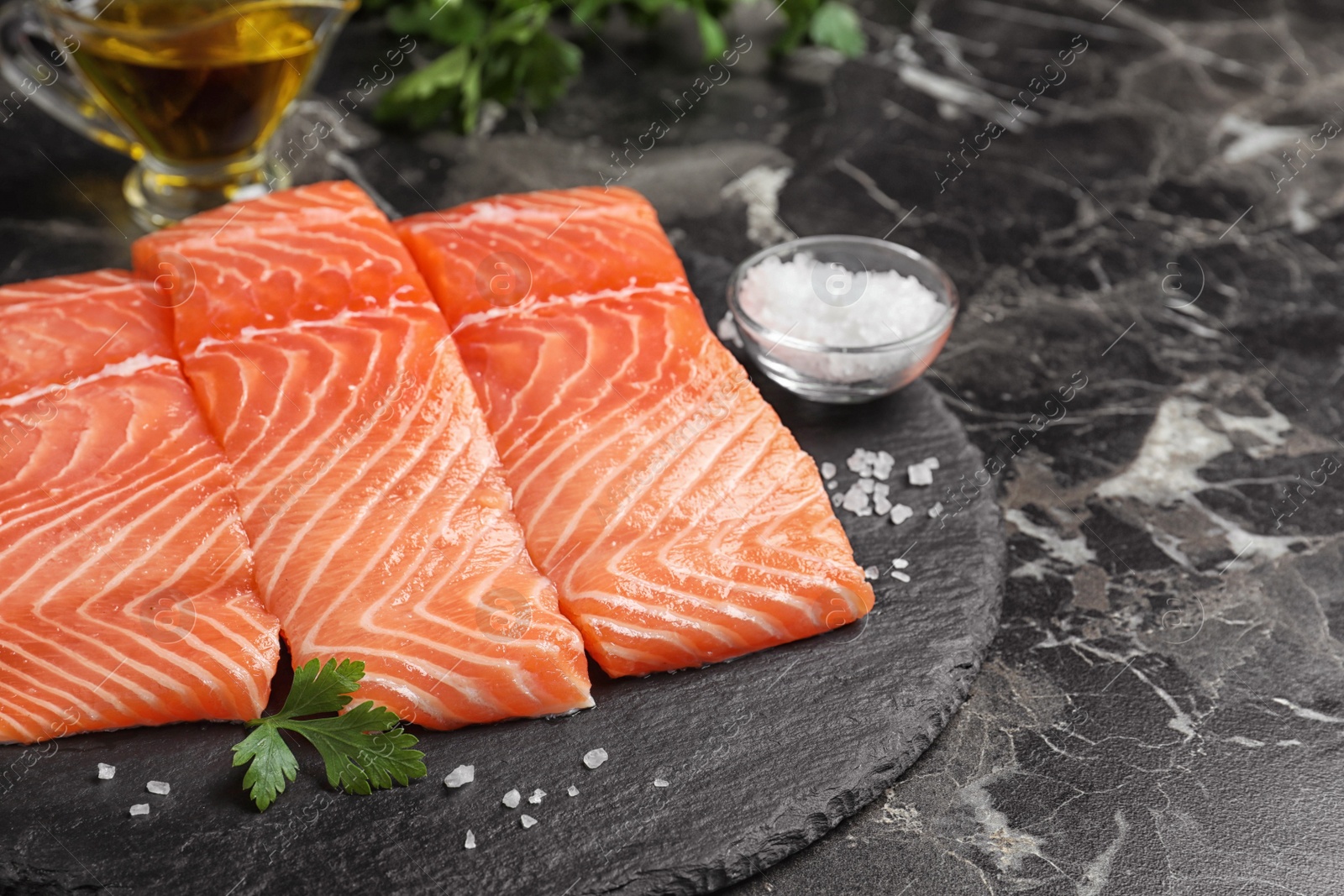 Fresh raw salmon with parsley and salt on black marble table. Fish delicacy Photo of Fresh raw salmon with parsley and salt on black marble table. Fish delicacy