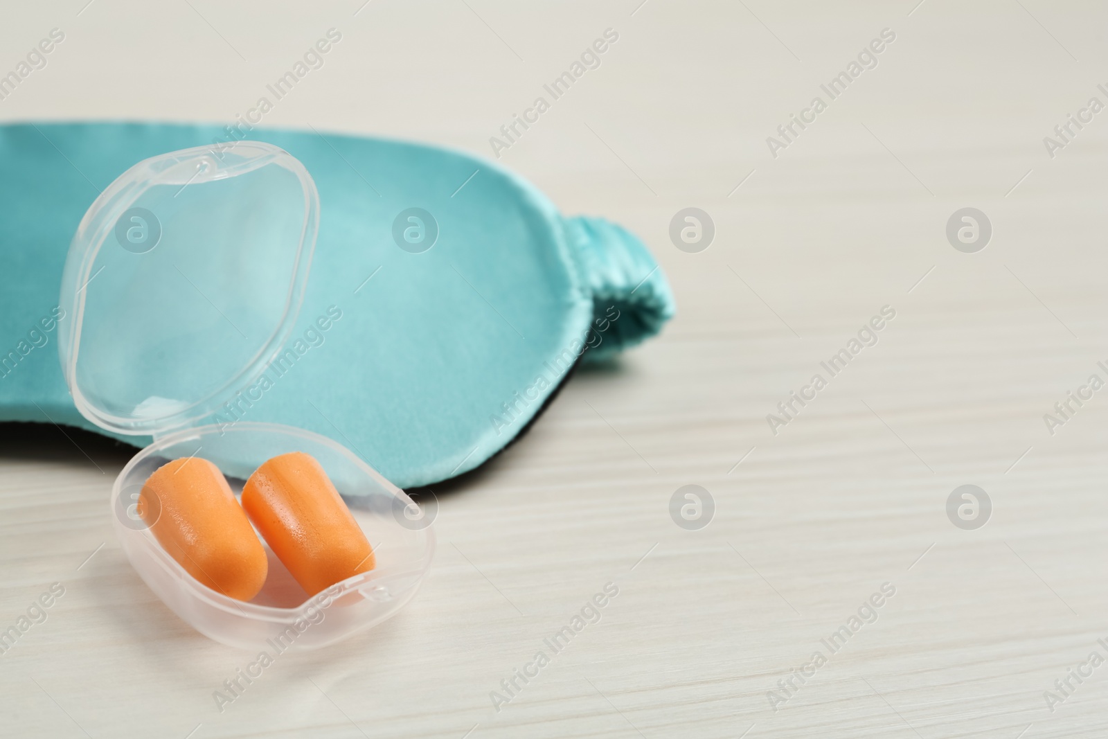 Pair of ear plugs and sleeping mask on white wooden background. Space for text Photo of Pair of ear plugs and sleeping mask on white wooden background. Space for text