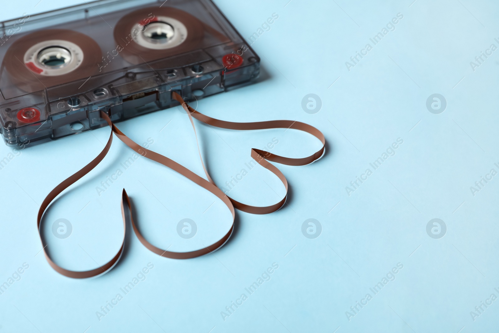 Music cassette and hearts made with tape on light blue background. Listening love song Photo of Music cassette and hearts made with tape on light blue background. Listening love song