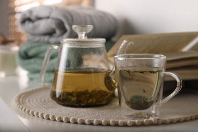 Glass teapot and cup of hot tea on table in room. Cozy home atmosphere Photo of Glass teapot and cup of hot tea on table in room. Cozy home atmosphere