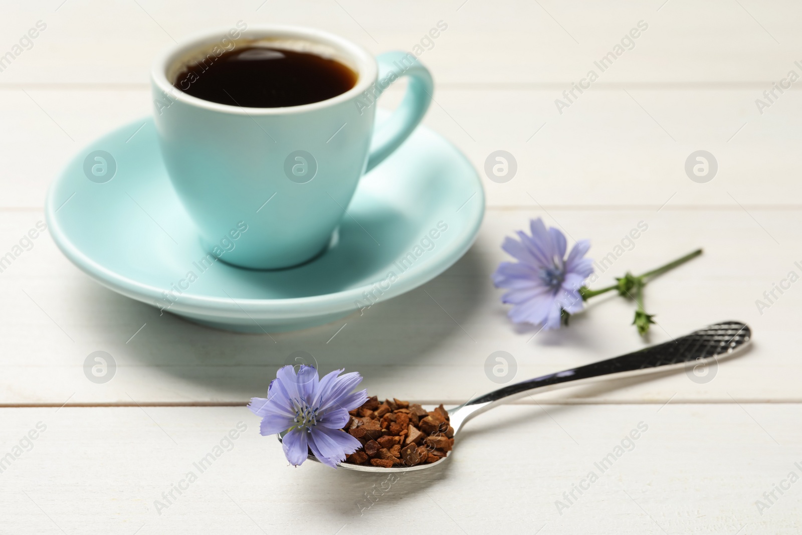 Spoon of chicory granules with flower on white wooden table Photo of Spoon of chicory granules with flower on white wooden table