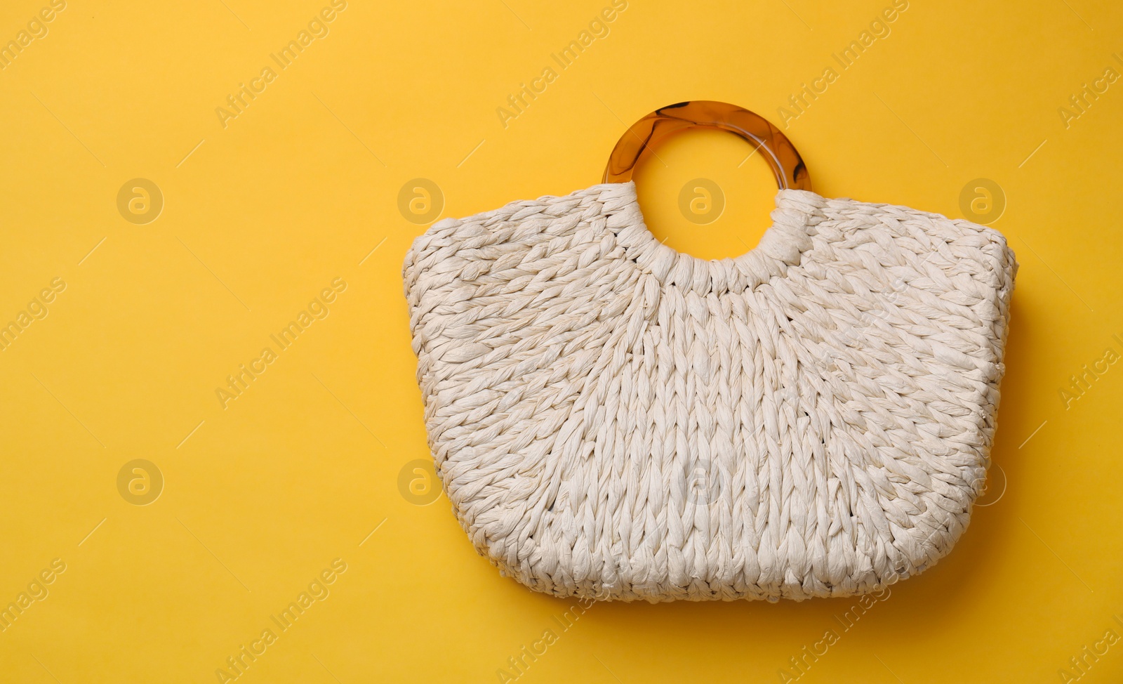 Photo of Stylish straw bag on yellow background, top view with space for text. Summer accessory