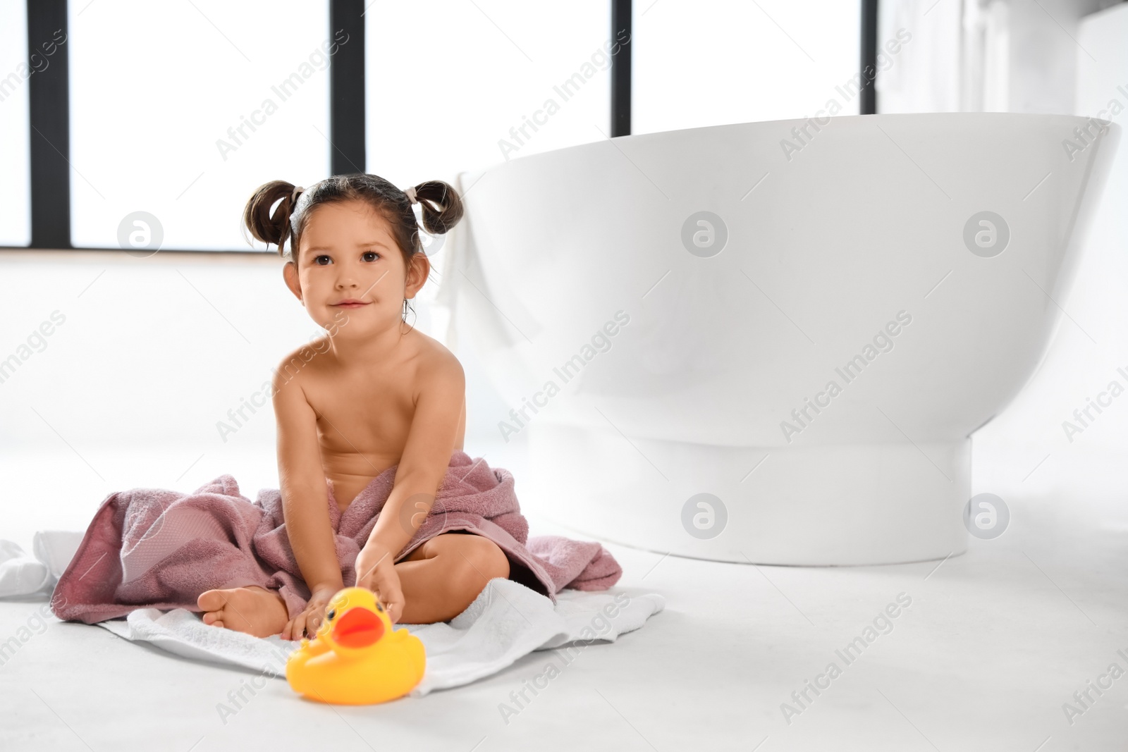 Photo of Cute little girl near tub in bathroom. Space for text