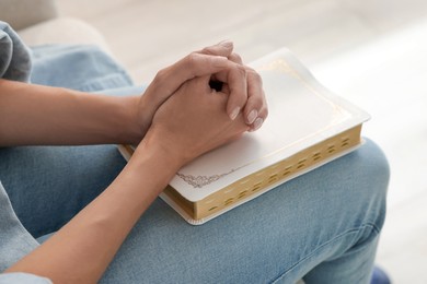 Religious woman with Bible praying indoors, closeup Photo of Religious woman with Bible praying indoors, closeup