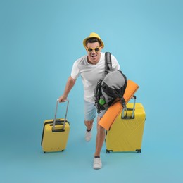Male tourist with travel backpack and suitcases running on turquoise background Photo of Male tourist with travel backpack and suitcases running on turquoise background