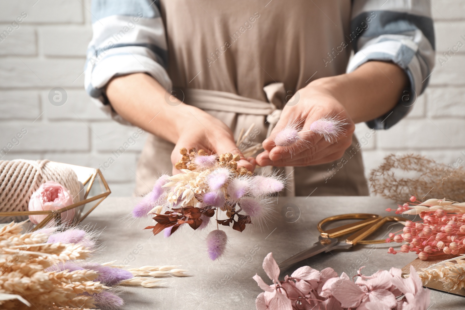 Florist making bouquet of dried flowers at grey stone table, closeup Photo of Florist making bouquet of dried flowers at grey stone table, closeup
