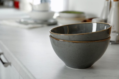 Beautiful ceramic bowls on white countertop in kitchen. Space for text Photo of Beautiful ceramic bowls on white countertop in kitchen. Space for text