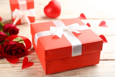 Beautiful gift box and roses on wooden table, closeup. Valentine's Day celebration Photo of Beautiful gift box and roses on wooden table, closeup. Valentine's Day celebration