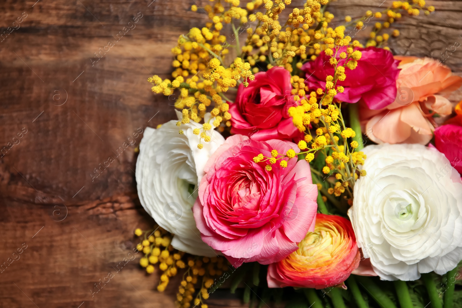 Beautiful ranunculus and mimosa flowers on wooden background Photo of Beautiful ranunculus and mimosa flowers on wooden background
