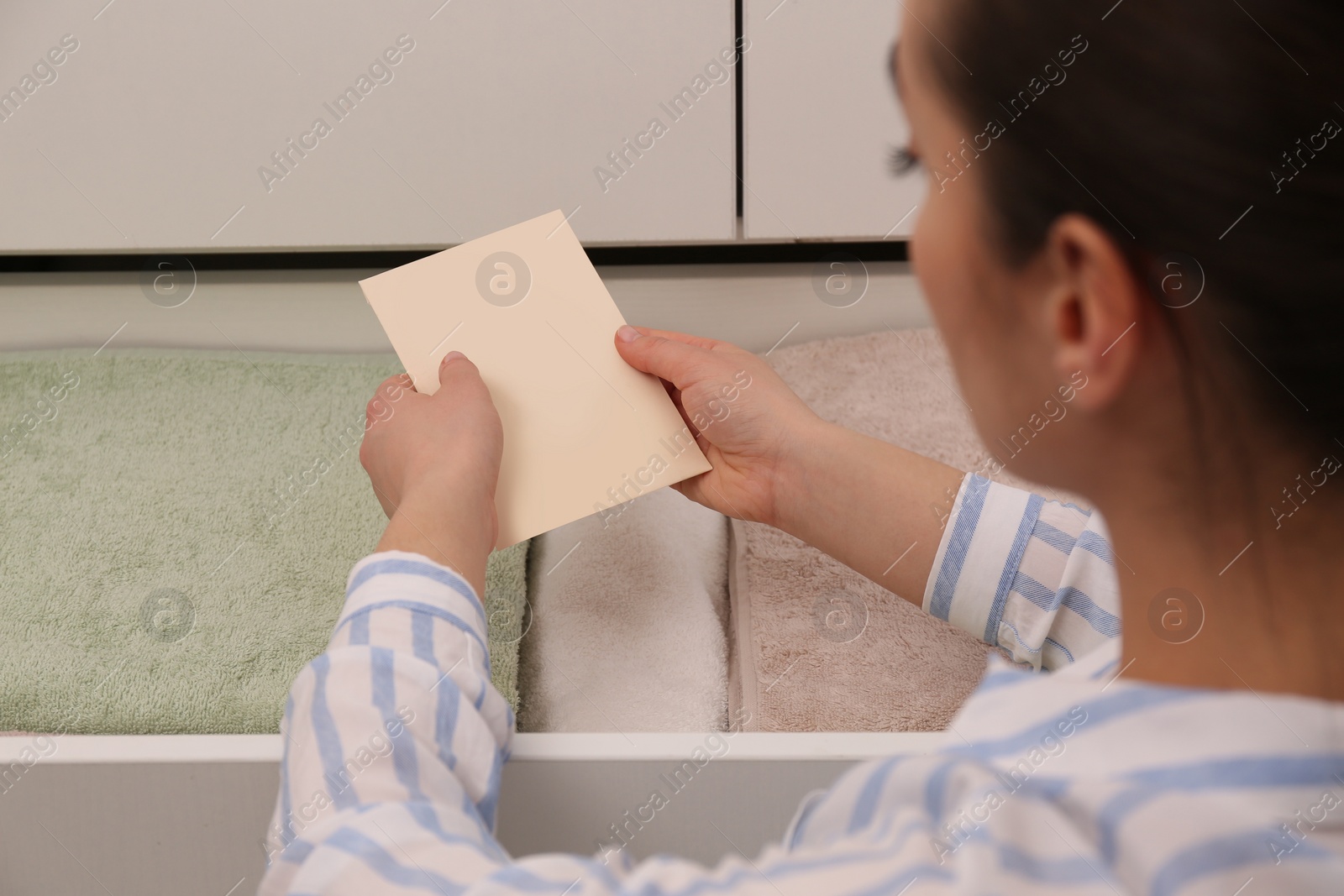 Woman putting scented sachet into drawer with towels Photo of Woman putting scented sachet into drawer with towels